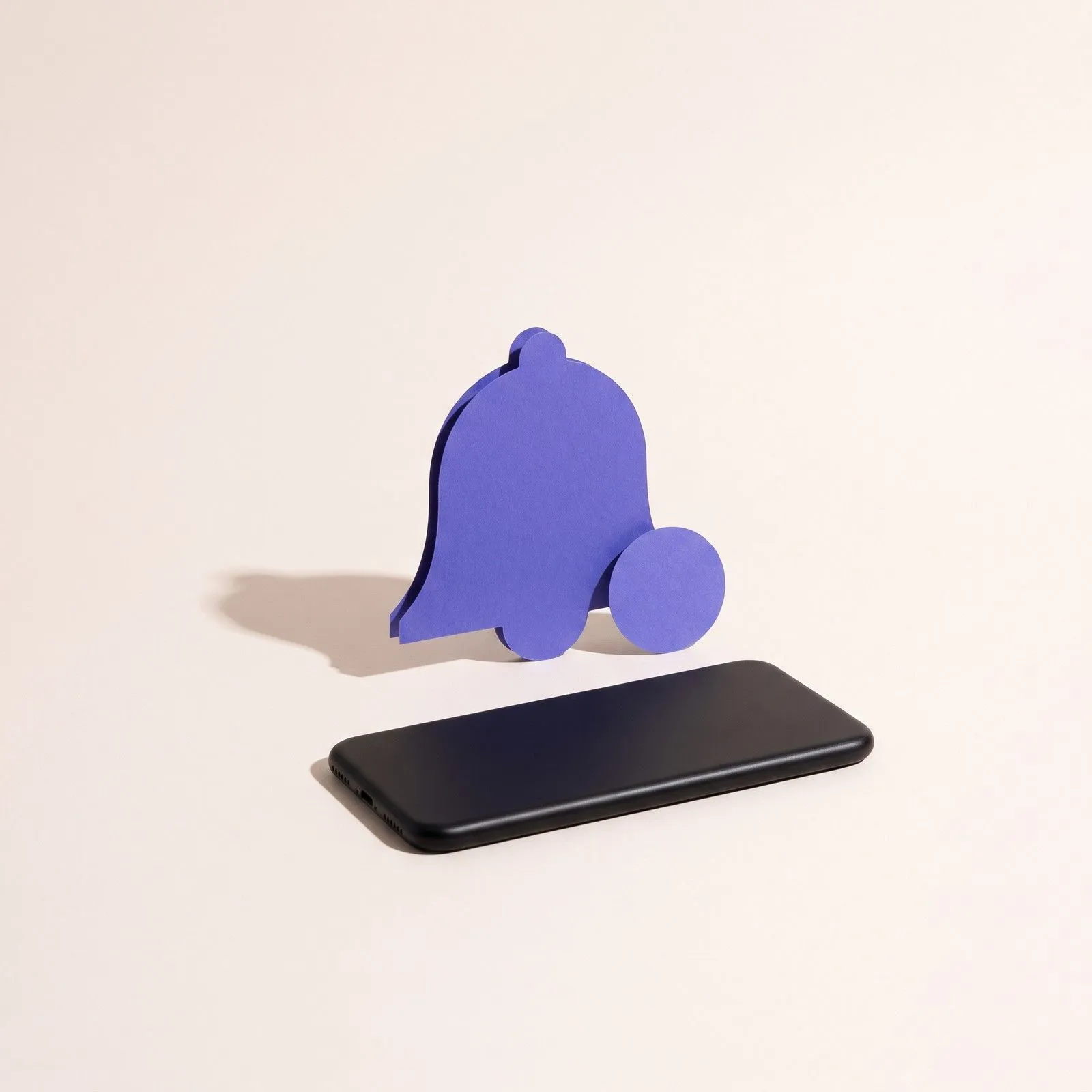 Eine violette Papierglocke mit kleinem Zählpunkt daneben, davor ein Smartphone mit dem Display nach unten